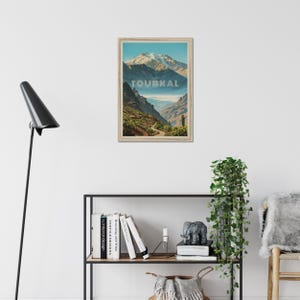 Peut inclure: Une affiche murale rectangulaire encadr&eacute;e repr&eacute;sentant une illustration paysag&egrave;re du mont Toubkal avec des sommets enneig&eacute;s, un terrain rocheux et un sentier sinueux. Le mot TOUBKAL est imprim&eacute; en grandes lettres majuscules claires au centre.