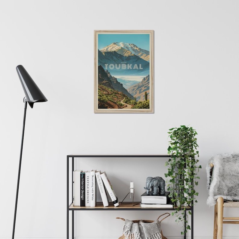 Peut inclure: Une affiche murale rectangulaire encadr&eacute;e repr&eacute;sentant une illustration paysag&egrave;re du mont Toubkal avec des sommets enneig&eacute;s, un terrain rocheux et un sentier sinueux. Le mot TOUBKAL est imprim&eacute; en grandes lettres majuscules claires au centre.