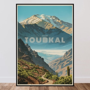 Peut inclure: Une affiche de voyage encadr&eacute;e pr&eacute;sentant une illustration stylis&eacute;e du mont Toubkal avec des sommets enneig&eacute;s, des montagnes bleu fonc&eacute; escarp&eacute;es et un sentier sinueux &agrave; travers la v&eacute;g&eacute;tation verte. Le texte MOUNT TOUBKAL est centr&eacute; en blanc.
