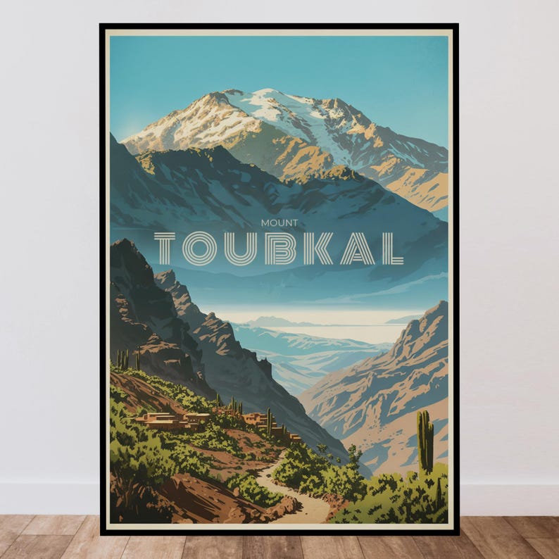 Peut inclure: Une affiche de voyage encadr&eacute;e pr&eacute;sentant une illustration stylis&eacute;e du mont Toubkal avec des sommets enneig&eacute;s, des montagnes bleu fonc&eacute; escarp&eacute;es et un sentier sinueux &agrave; travers la v&eacute;g&eacute;tation verte. Le texte MOUNT TOUBKAL est centr&eacute; en blanc.