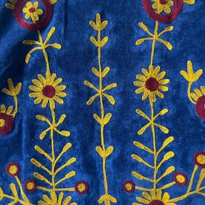 May include: Close-up of a blue textile with embroidered floral patterns in yellow and maroon. The design features stylized sunflowers and other floral elements. The text "MMArtisanstudioindia" is visible at the bottom.
