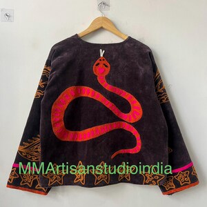 Puede incluir: Top de manga larga marr&oacute;n oscuro con un gran dise&ntilde;o de serpiente bordada en tonos rosa y naranja. Las mangas y el dobladillo presentan bordados decorativos en naranja. El texto "MMArtisanstudioindia" est&aacute; impreso en la parte inferior.
