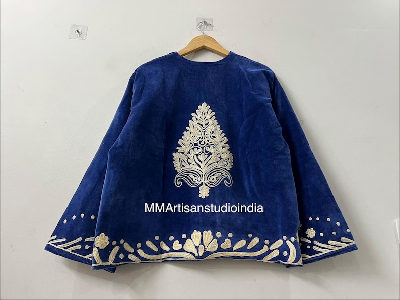 May include: A royal blue jacket featuring a central cream-colored embroidered tree motif on the back. The hem and sleeve cuffs are decorated with cream-colored floral and dot embroidery. The text MMArtisanstudioindia is printed in white.