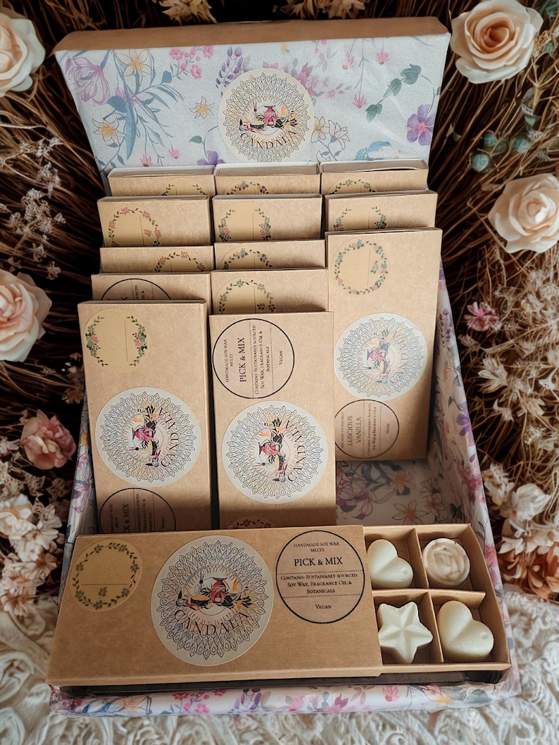 May include: A decorative box filled with handmade soy wax melts. The box contains several small, rectangular boxes with floral designs and circular stickers. The bottom box holds heart and star-shaped wax melts. The text "PICK & MIX" is visible.