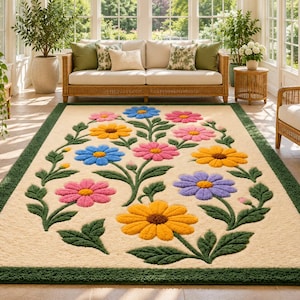 May include: A rectangular area rug with a cream-colored center featuring a tufted floral pattern of pink, blue, yellow, and purple daisies with green stems and leaves, all framed by a solid dark green border.