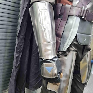 Pu&ograve; includere: Un pezzo per braccio da costume argentato e nero con un design testurizzato. Il pezzo per braccio ha un triangolo blu sul retro della mano.