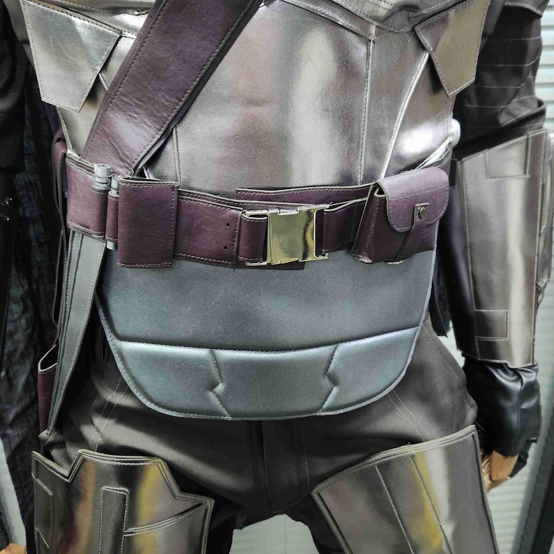 Pu&ograve; includere: Un costume in pelle argentata e marrone con cintura e fibbia. Il costume ha una finitura testurizzata, metallica e un pezzo toracico imbottito.