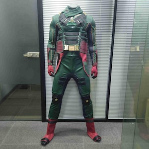 Könnte beinhalten: Ein grünes und rotes Superhelden-Kostüm mit schwarzen Akzenten. Das Kostüm verfügt über einen hohen Kragen, ein Bruststück mit einem Stern und Knieschoner mit Sternen. Das Kostüm ist aus dehnbarem Material gefertigt und hat eine figurbetonte Silhouette.