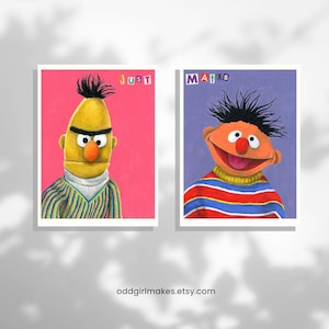 May include: Two framed prints featuring Sesame Street characters. One print shows a yellow character with the word "JUST" above it. The other print shows an orange character with the word "MATES" above it. The Etsy shop URL is visible at the bottom.
