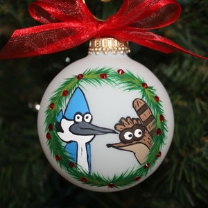 Ornement personnalisé en verre peint à la main avec les spectacles réguliers Mordecai et Rigby regardant à travers une couronne de Noël