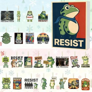 May include: A collection of frog-themed ornaments with various designs and the word "RESIST". Some ornaments feature text like "FROGS AGAINST FASCISM" and "RAGE AGAINST THE MACHINE". The ornaments are green, white, and black.