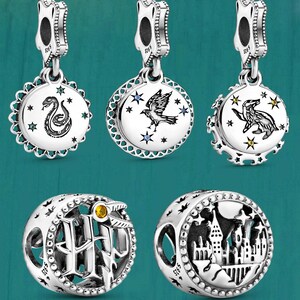 May include: Six silver charms with various designs. Three charms have circular pendants with images of a snake, bird, and badger. The other three charms are spherical, one with the letters HP and a snake, and the other with a castle.