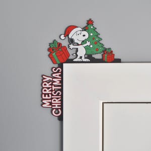 May include: A Christmas-themed corner decoration featuring Snoopy wearing a Santa hat, a green Christmas tree, and red gift boxes. The words "MERRY CHRISTMAS" are displayed vertically on the side.