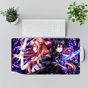 Puede incluir: Una alfombrilla de rat&oacute;n rectangular con dos personajes de anime con espadas, sobre un fondo morado y negro. Los personajes tienen pelo largo y visten trajes detallados. Se ven un teclado y un rat&oacute;n blancos.