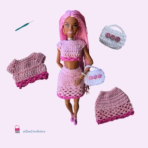 May include: A doll wearing a pink crochet crop top and skirt set, with a matching purse. Additional crochet pieces include a top and skirt. The doll has pink hair and is accessorized with gold jewelry. A crochet hook is also visible.