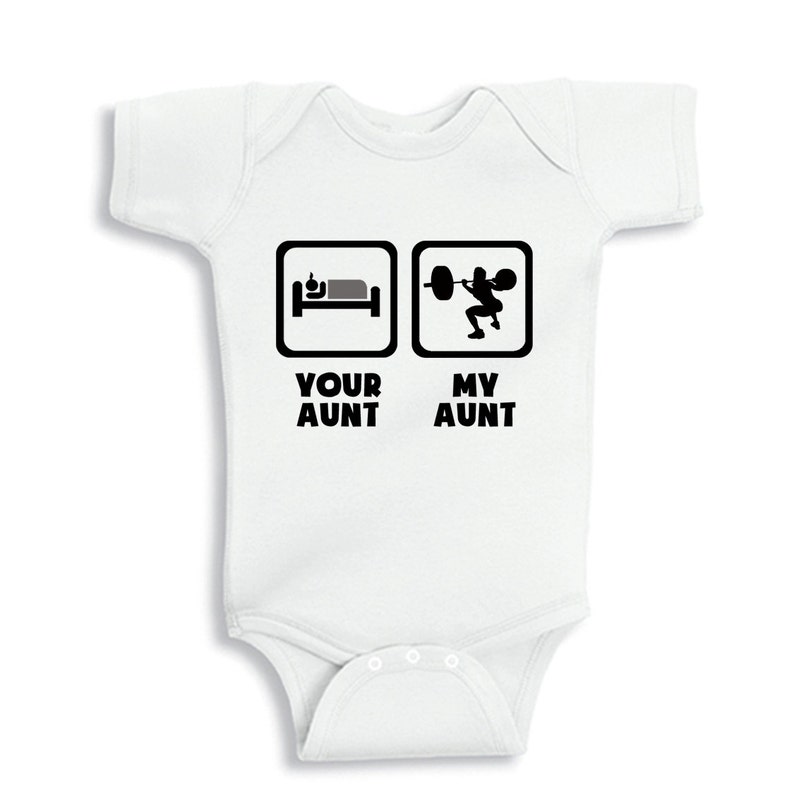 May include: White baby onesie with black text that reads "Your Aunt" and "My Aunt". The left side of the onesie has a black and white icon of a bed with a person sleeping in it. The right side of the onesie has a black and white icon of a person lifting weights.