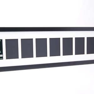 May include: Black picture frame with white matting and eight openings for 4x6 photos. The frame has a label that reads "Holds Your 4x6 Photographs with matting included - Full Strength Glass - Acid Free Backing and Hardware for Hanging - Creative Frames"
