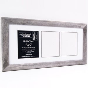 May include: A gray wooden picture frame designed to hold two 5x7 inch photographs. The frame has a white mat and a black label that reads "Holds Your 5x7 Photographs Perfectly". The frame is made in the USA.