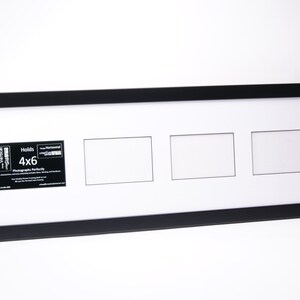 May include: Black picture frame with three 4x6 inch openings. The frame is made of wood and has a matte finish. The frame is designed to hold photographs.