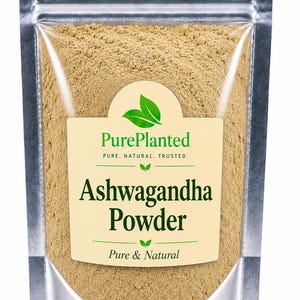 May include: A silver pouch filled with light brown ashwagandha powder. The pouch has a clear window and a label with the text "PurePlanted" and "Ashwagandha Powder". The label also states "Pure & Natural".