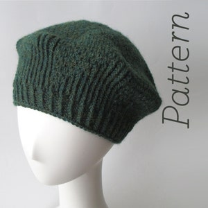 May include: A dark green knitted beret with a ribbed texture. The beret is on a white mannequin head.