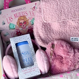 Peut inclure: Coffret cadeau rose contenant un sac à dos en peluche, des cache-oreilles, un ensemble de tasses de voyage et un livre. La tasse de voyage porte l'inscription "Baby It's Cold Outside".