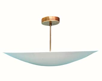 May include: A modern ceiling light fixture with a brass-colored canopy and stem. The light has a wide, shallow, bowl-shaped shade in a pale blue color. The fixture is suspended from the ceiling.