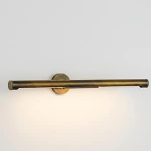 Könnte beinhalten: Eine Bildleuchte im Vintage-Stil, in Messingoptik. Sie hat einen langen, zylindrischen Arm und eine kreisförmige Montageplatte. An einer weißen Wand montiert, verströmt sie ein warmes Licht, ideal für Kunstwerke.