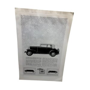 May include: A vintage advertisement featuring a black car with a white top, set against a floral patterned background. The ad includes text and smaller car illustrations, showcasing a classic automobile design.