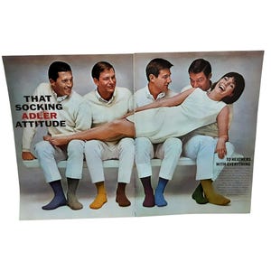 May include: Vintage advertisement featuring four people, three men and one woman, seated on a bench. The men wear white sweaters and pants, each with a different colored sock: blue, gray, yellow, and brown. The woman wears a white dress. Text reads "THAT SOCKING ADLER ATTITUDE."