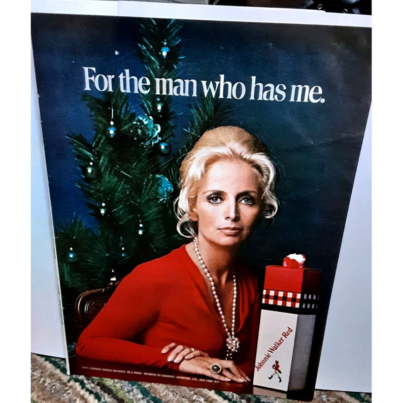 Pode incluir: An&uacute;ncio vintage com uma mulher em um vestido vermelho, colar de p&eacute;rolas, anel e uma &aacute;rvore de Natal. O texto diz: "Para o homem que me tem". Uma garrafa de Johnnie Walker Red tamb&eacute;m &eacute; vis&iacute;vel.