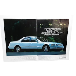 May include: A light blue Acura Legend sedan is featured in an advertisement. The text reads, "Forget everything you've heard about the Acura Legend. Our engineers did." The car is parked on a road with trees in the background.