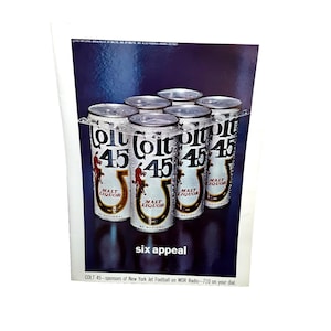 May include: Six cans of Colt 45 Malt Liquor in a clear plastic holder. The cans are silver with bold black and white text and a red graphic. The text "six appeal" is below the cans.