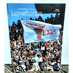 May include: A vintage University of Texas Longhorns football program cover featuring a crowd of fans holding a large blue and red flag with the words "Hook 'em Horns" and "Texas".