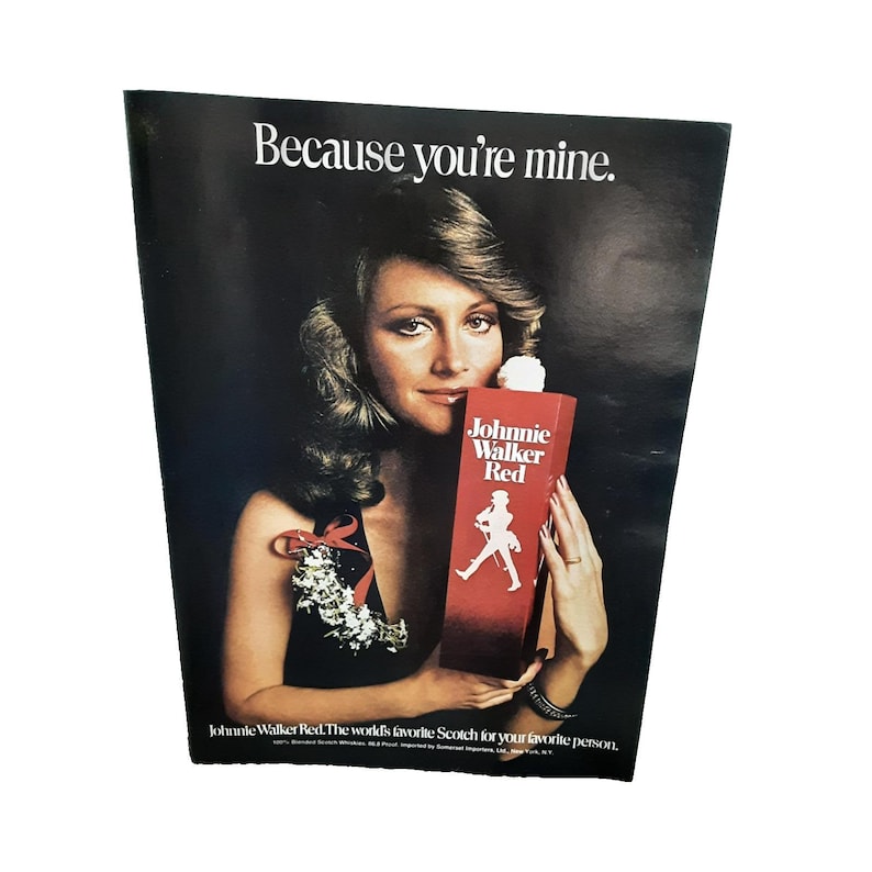 K&ouml;nnte beinhalten: Vintage Werbung f&uuml;r Johnnie Walker Red Scotch. Das Bild zeigt eine Frau, die eine rote Flasche Johnnie Walker Red h&auml;lt. Der Text lautet "Because you're mine."