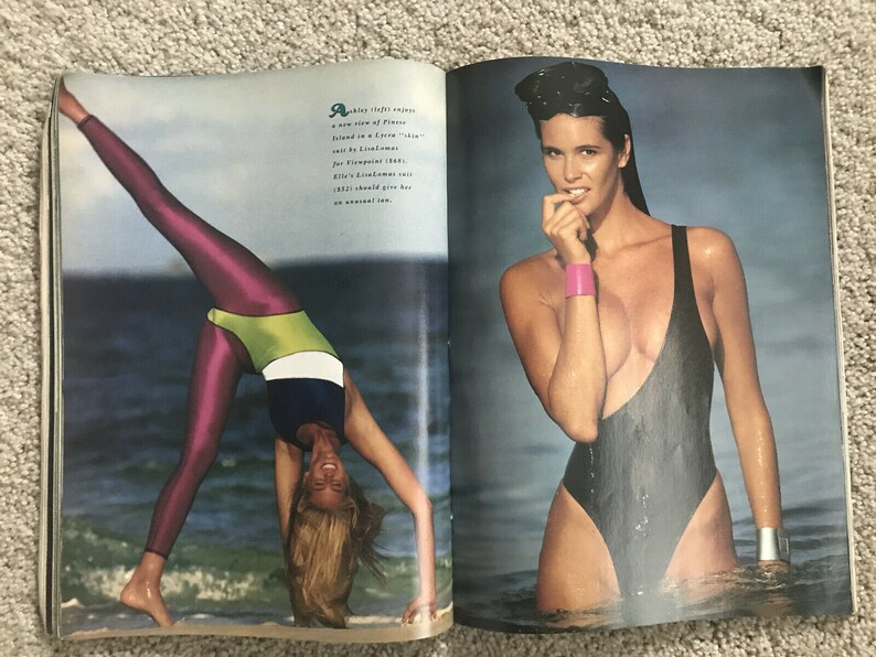Puede incluir: Dos mujeres con trajes de ba&ntilde;o. Una mujer lleva un traje de ba&ntilde;o negro y est&aacute; de pie en el agua. La otra mujer lleva un traje de ba&ntilde;o rosa y verde y est&aacute; haciendo una pose de yoga en la playa.