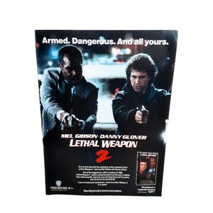 May include: A promotional poster for the film Lethal Weapon 2 featuring Mel Gibson and Danny Glover holding handguns. The text reads: Armed. Dangerous. And all yours. Lethal Weapon 2. Mel Gibson. Danny Glover. Warner Home Video. 1989.