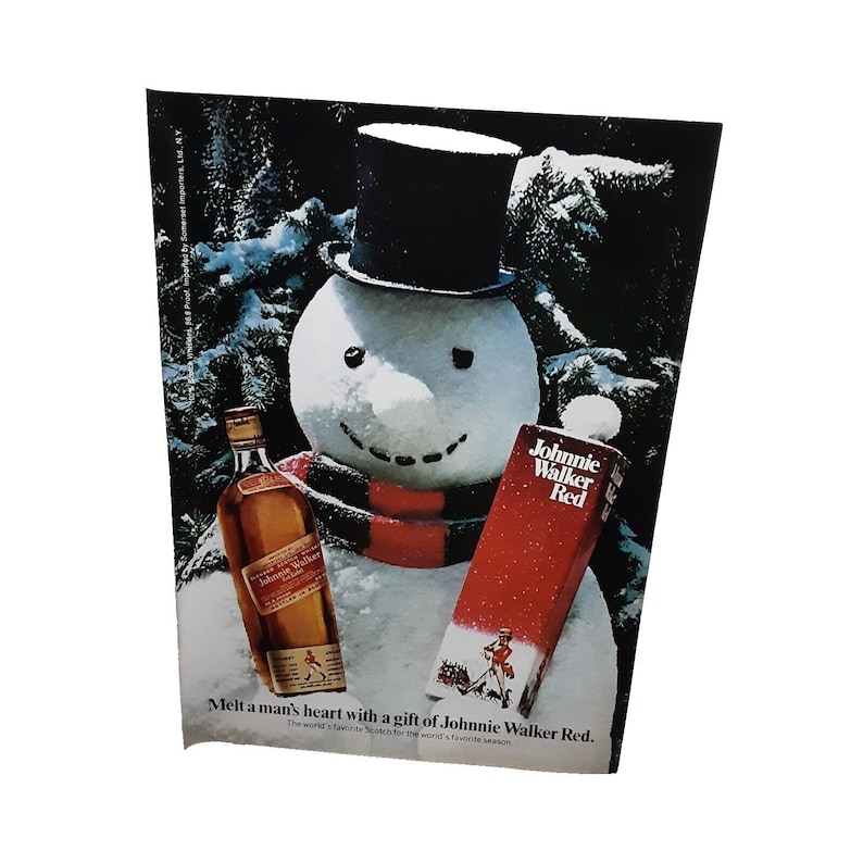 Pu&ograve; includere: Un pupazzo di neve che tiene una bottiglia di whisky scozzese Johnnie Walker Red. Il pupazzo di neve indossa un cappello a cilindro nero e una sciarpa rossa. Il testo sulla bottiglia recita "Johnnie Walker Red". Il testo sotto il pupazzo di neve recita "Sciogli il cuore di un uomo con un regalo di Johnnie Walker Red. Lo Scotch preferito al mondo per la stagione preferita al mondo."