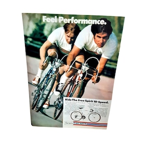 May include: An advertisement featuring two cyclists racing on Free Spirit 10-speed bicycles. The cyclists wear white shirts and are in motion. The text "Feel Performance" is at the top. The ad includes the text "Ride The Free Spirit 10-Speed."