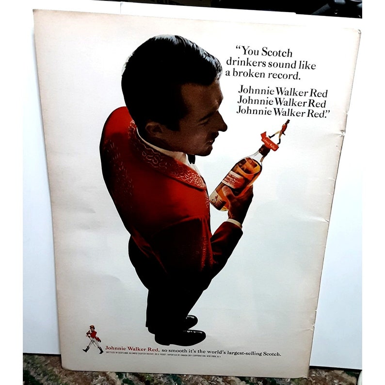 May include: A man in a red suit holds a bottle of Johnnie Walker Red Scotch whisky. The text on the ad reads "You Scotch drinkers sound like a broken record. Johnnie Walker Red. Johnnie Walker Red. Johnnie Walker Red."  The ad also states "Johnnie Walker Red, so smooth it's the world's largest-selling Scotch."