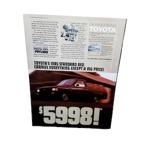 May include: A vintage advertisement for the 1985 Toyota Standard Bed pickup truck. The ad features a brown truck driving on a paved road with a caption that reads "Toyota's 1985 Standard Bed. Carries everything except a big price!" and a price tag of $5998. The ad also highlights the truck's features, including its 1400 lbs payload, 2.4 liter engine, and power assisted disc brakes.