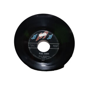 May include: Black vinyl record with a label that says "Blue Tango" by Bill Black's Combo. The label has a red and blue musical note design and the text "Thelas" in a white box.