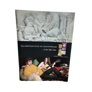 May include: An advertisement featuring a classical Roman relief at the top, with a couple relaxing below. The ad includes the text "You don't have to be an Ancient Roman...to live like one." and a bottle of cologne.