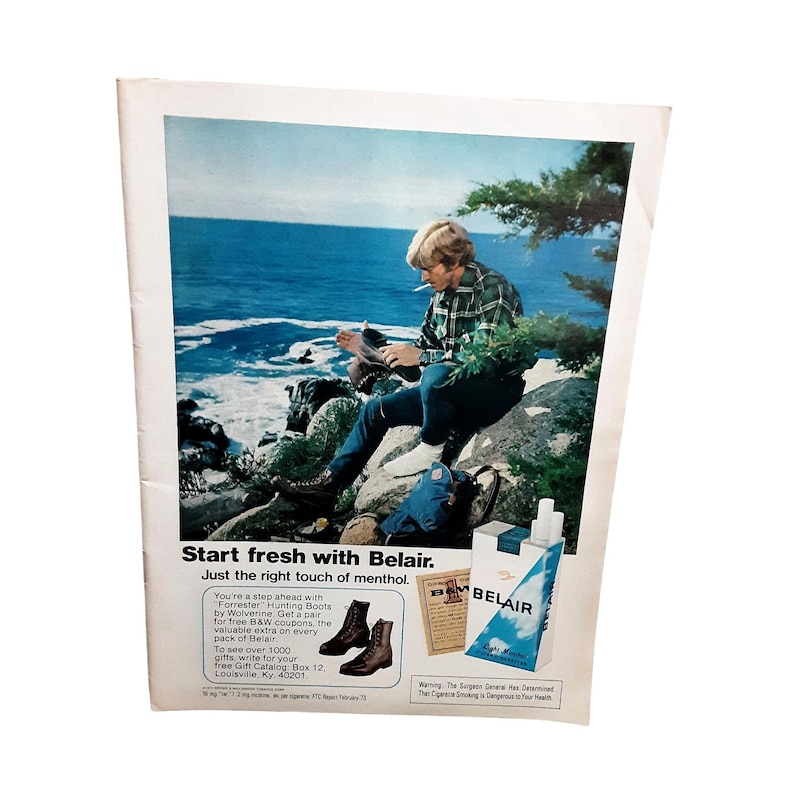 May include: Vintage magazine advertisement for Belair cigarettes. The ad features a person sitting on a rock by the ocean, smoking a cigarette. The ad also shows a pack of Belair cigarettes and a pair of brown boots.