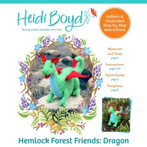 Könnte beinhalten: Ein grüner Filzdrache mit roten Flügeln und einem hellblauen Bauch. Der Drache sitzt auf einem Felsen in einer Waldlandschaft. Das Bild stammt aus einem Nähmuster für einen Hemlock Forest Friends: Dragon.