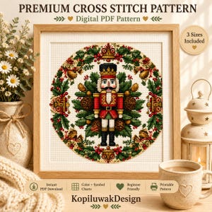 May include: A cross stitch pattern featuring a nutcracker centred within a circular wreath of holly, pinecones, and gold bells. The text reads PREMIUM CROSS STITCH PATTERN, Digital PDF Pattern, 3 Sizes Included, Instant PDF Download, and KopiluwakDesign.