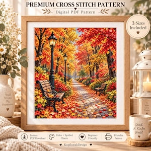Op de afbeelding: Een ingelijst kruissteekpatroon getiteld PREMIUM CROSS STITCH PATTERN Digital PDF Pattern met een levendige herfstparkscène met een kasseienpad, zwarte banken en straatlantaarns omringd door rode, oranje en gele esdoorns.