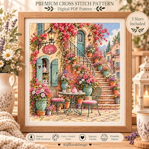 May include: A digital cross stitch pattern featuring a cafe scene with a stone staircase, pink flowers, teal shutters, and a wrought iron table set. The framed artwork displays the text Premium Cross Stitch Pattern, Digital PDF Pattern, and 3 Sizes Included.