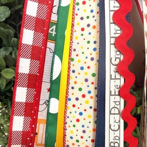May include: A collection of vertical fabric ribbons featuring various patterns including red and white gingham, green with white polka dots, a solid yellow strip, a cream ribbon with multicolored dots, a navy blue edge, and a red rickrack trim.