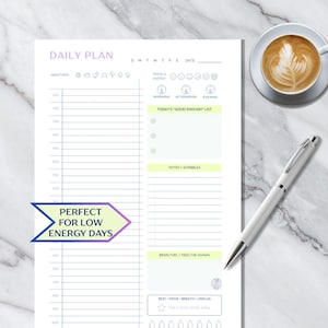 Peut inclure: Un planificateur quotidien blanc avec un en-tête violet clair indiquant "DAILY PLAN". Le planificateur comprend des sections pour la météo, l'humeur, l'énergie et une "Today's Good Enough List". Un stylo blanc et une tasse de café avec du latte art sont à côté du planificateur.